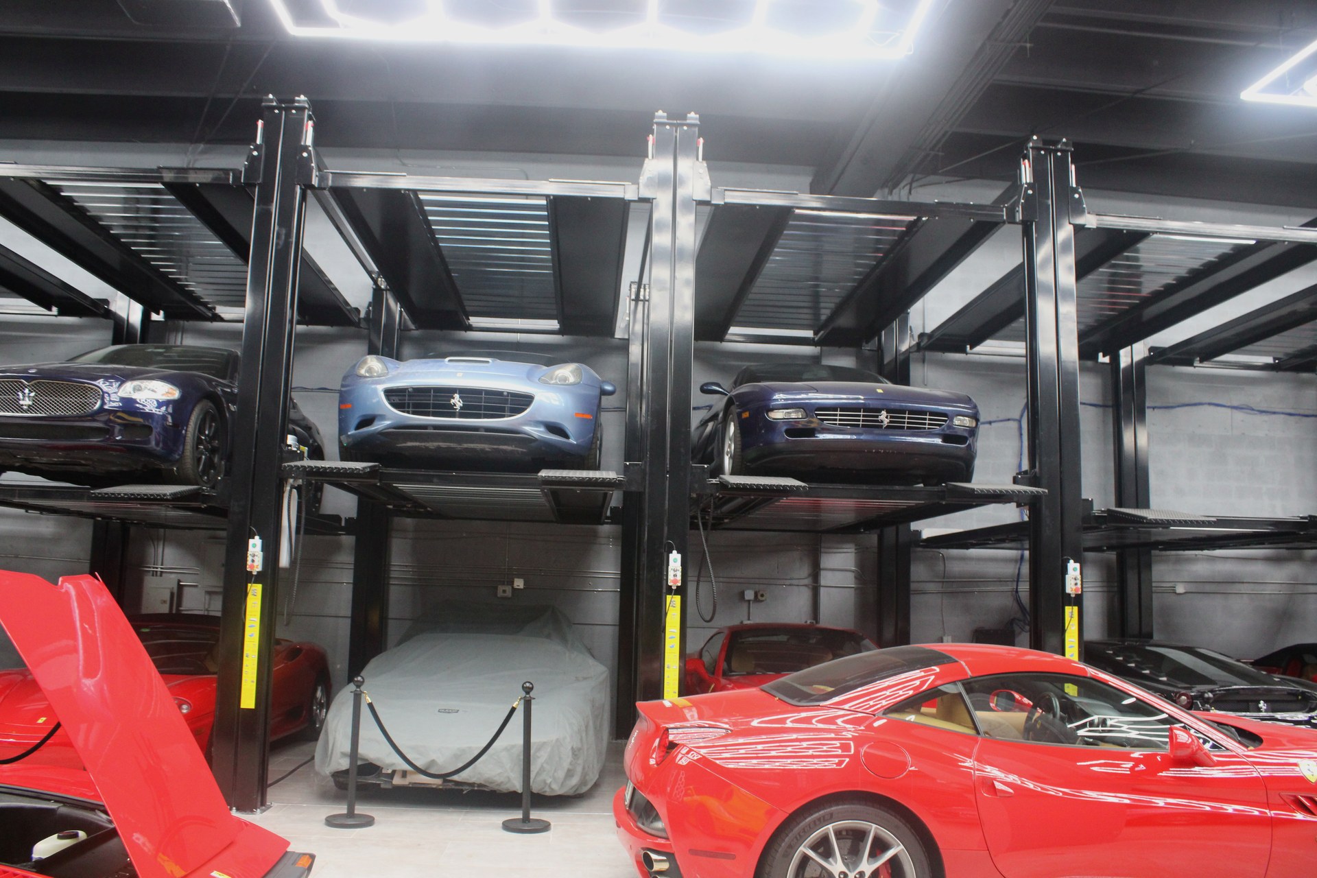 Multi-tier lift system holding Ferrari and Maserati