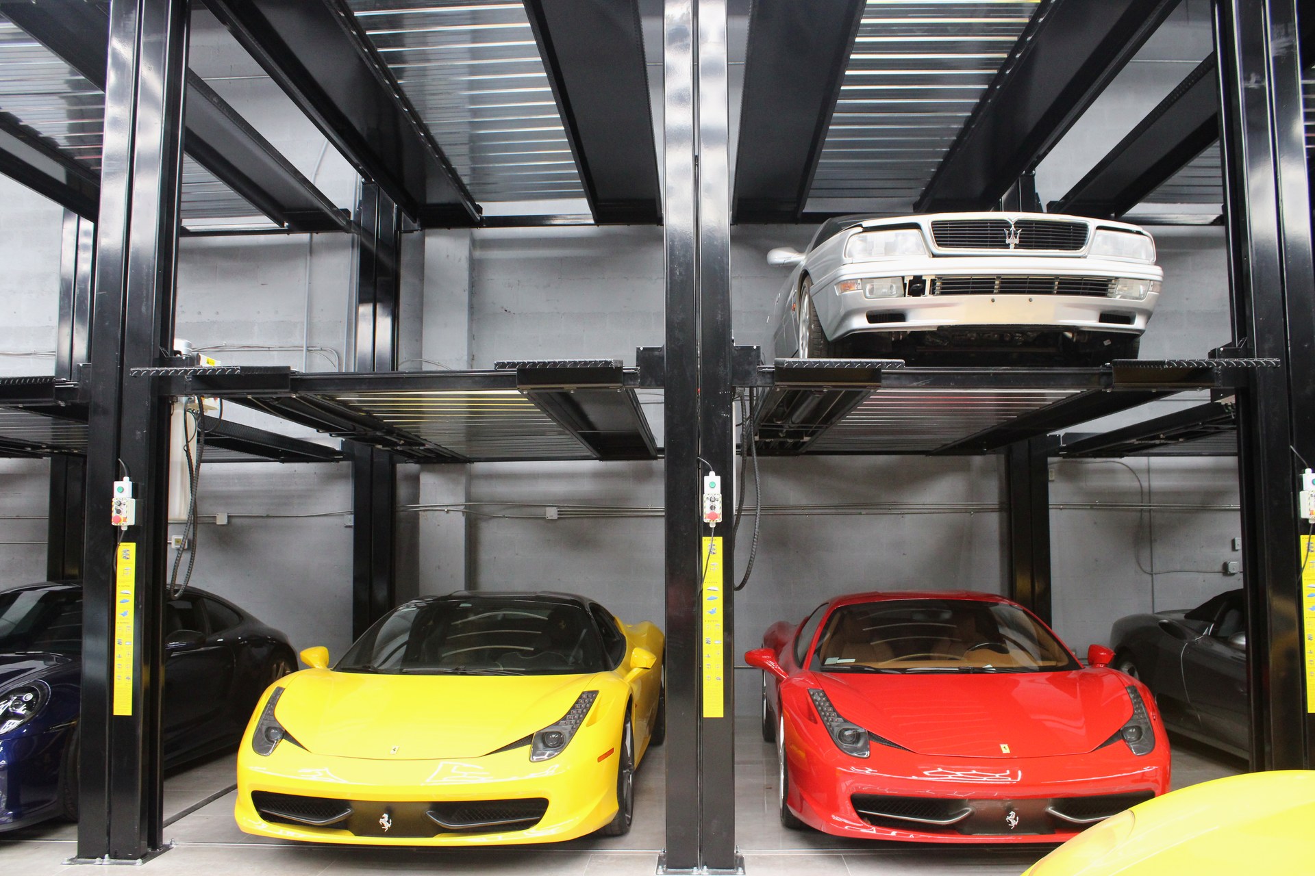 Yellow and red Ferrari 458 beneath a classic on a lift