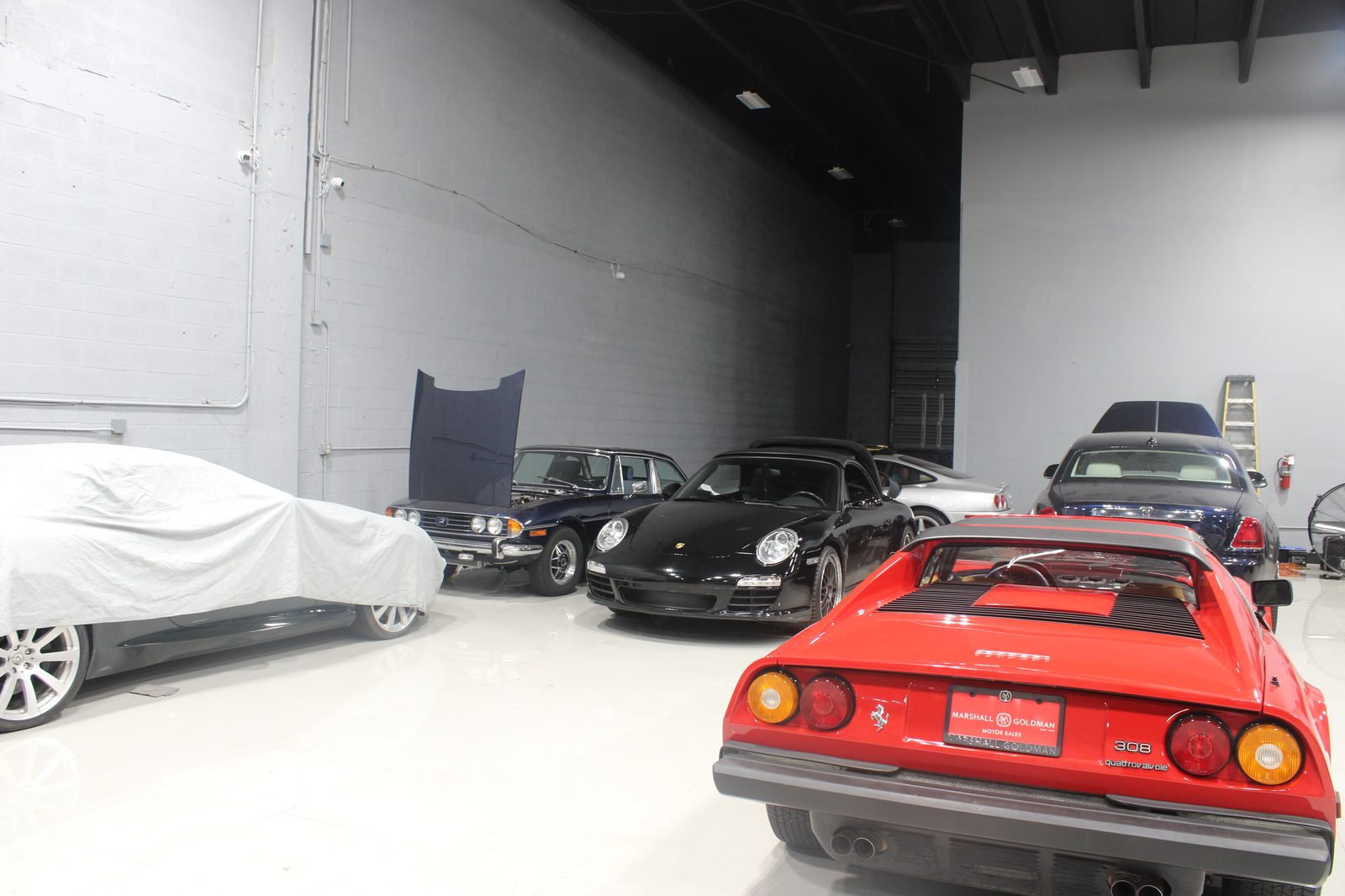 Storage row with covered vehicles, vintage Porsche, and Ferrari 308