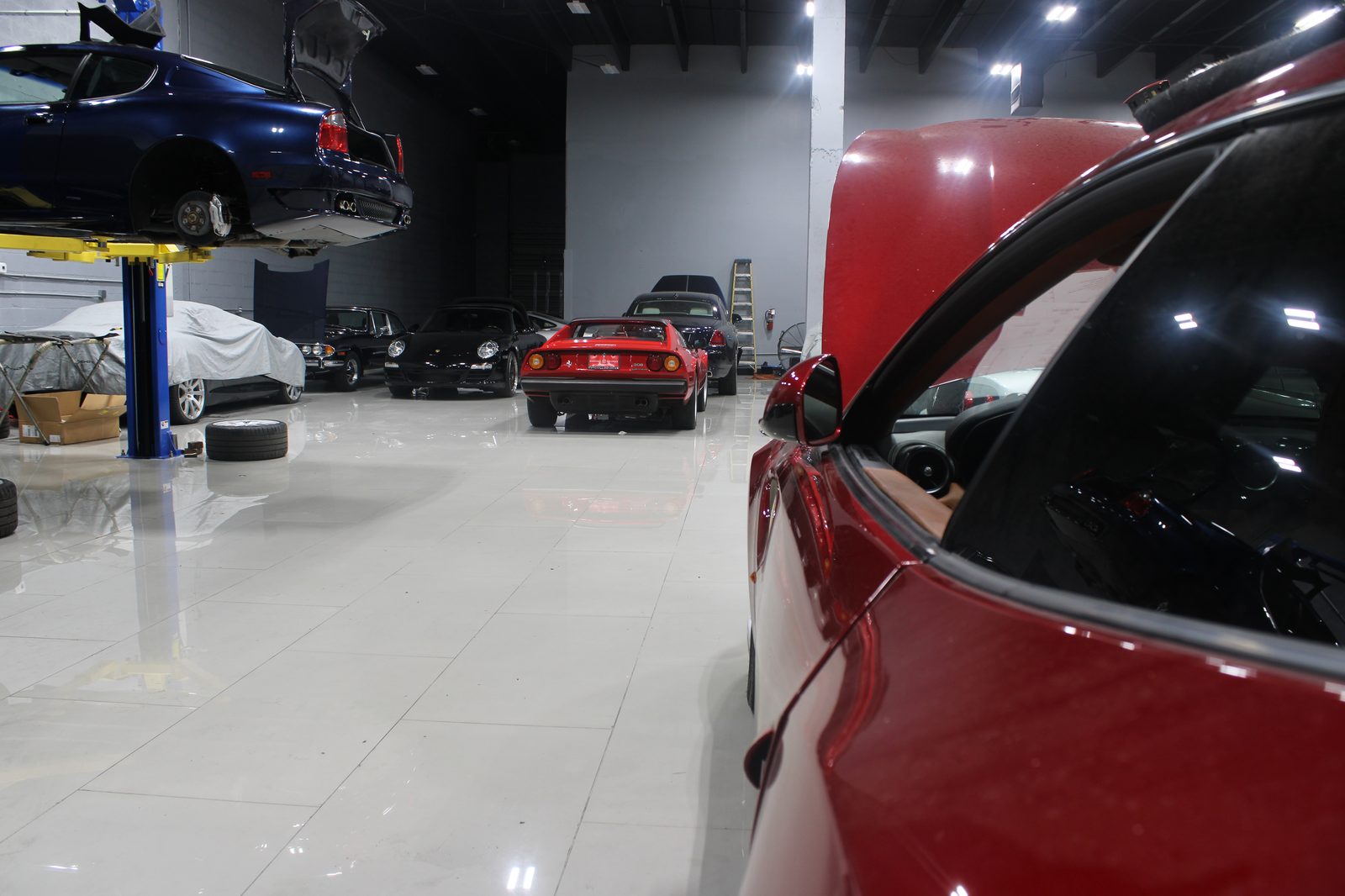 Blue Maserati on lift, Ferrari 308 in foreground