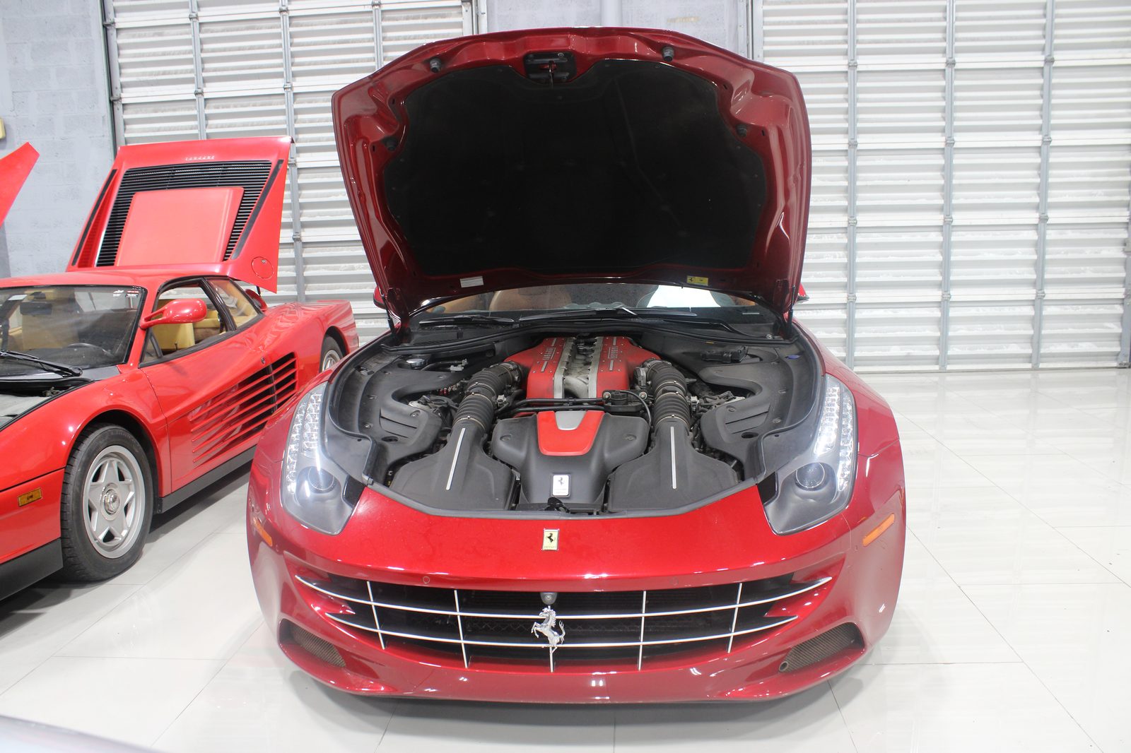 Ferrari FF with hood open beside a Testarossa